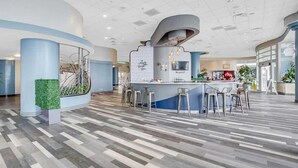 Eine moderne Hotelhalle mit Barbereich, Sitzgelegenheiten und einer Wanddekoration.