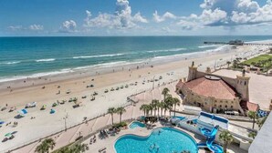 Ein Strandresort mit Schwimmbad, Strand und einem schlossähnlichen Gebäude.