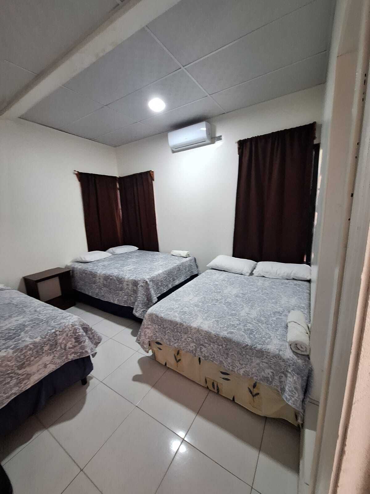 A room with three beds, a ceiling fan, and an air conditioning unit.