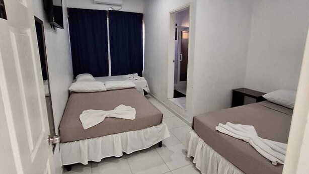 A hotel room with two beds, a TV, an air conditioning unit, and a door.