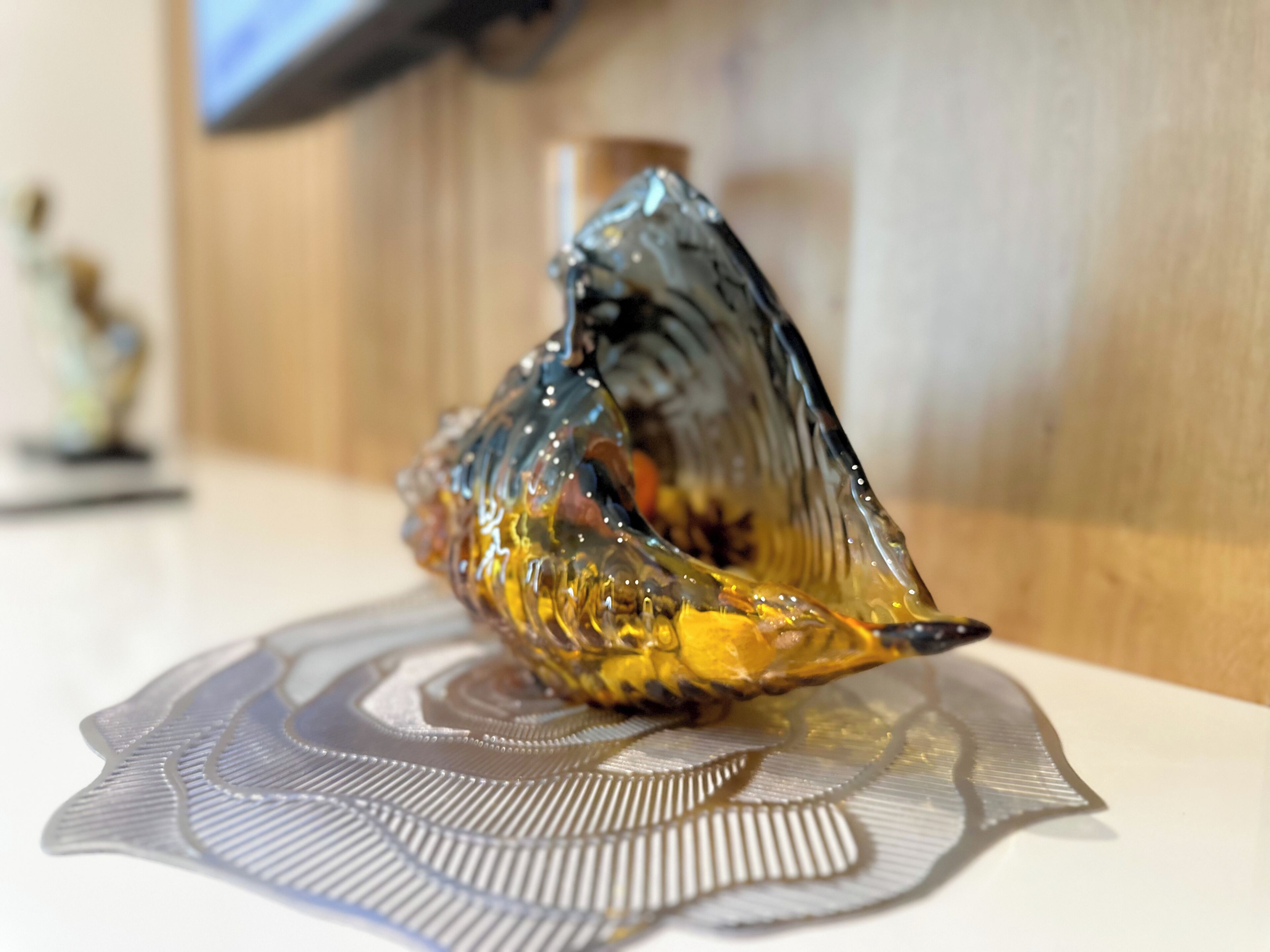 Un objet décoratif en verre posé sur une table, accompagné d’un set de table à motifs.