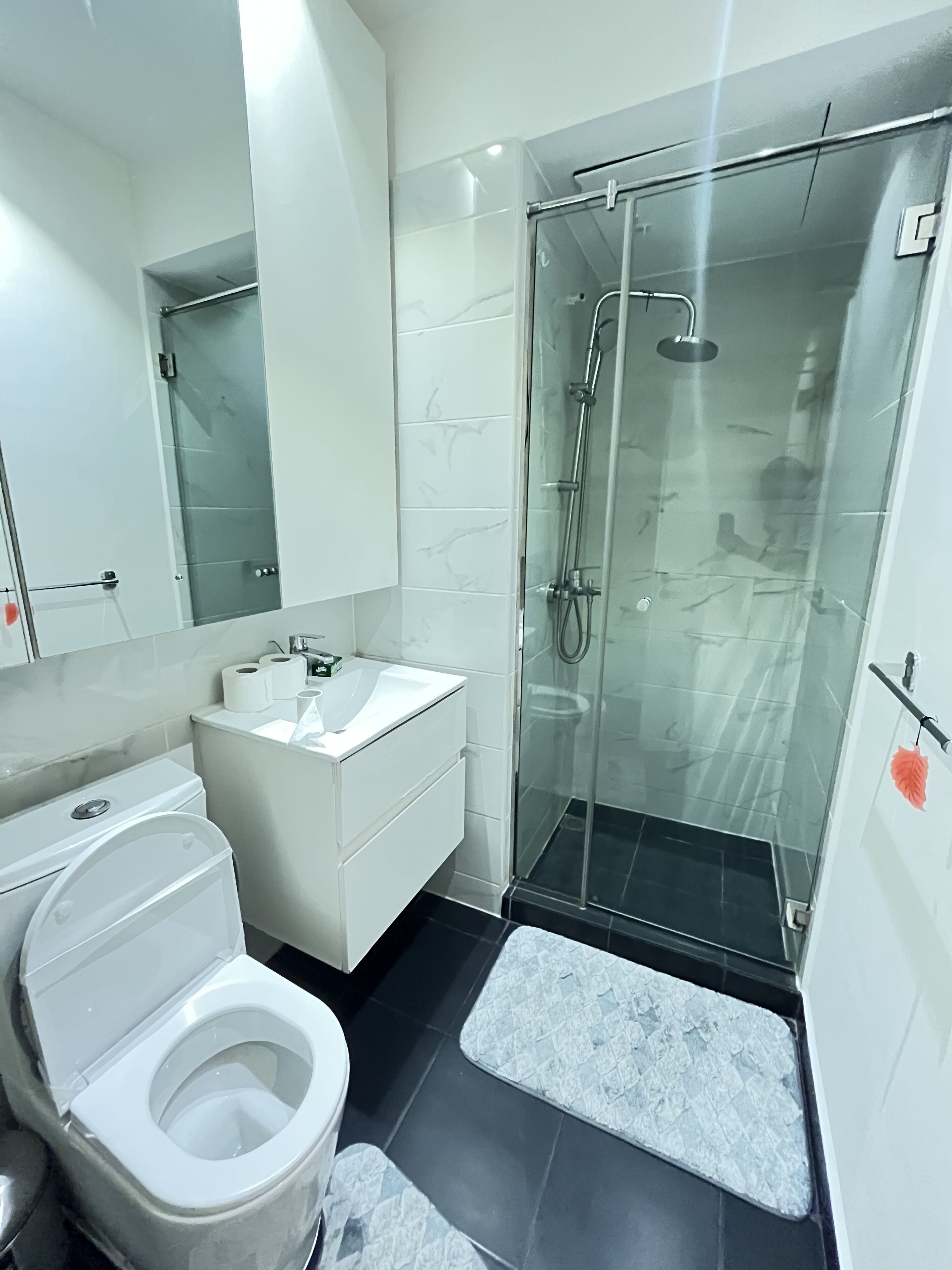 A modern bathroom with a toilet, sink, and glass-enclosed shower.