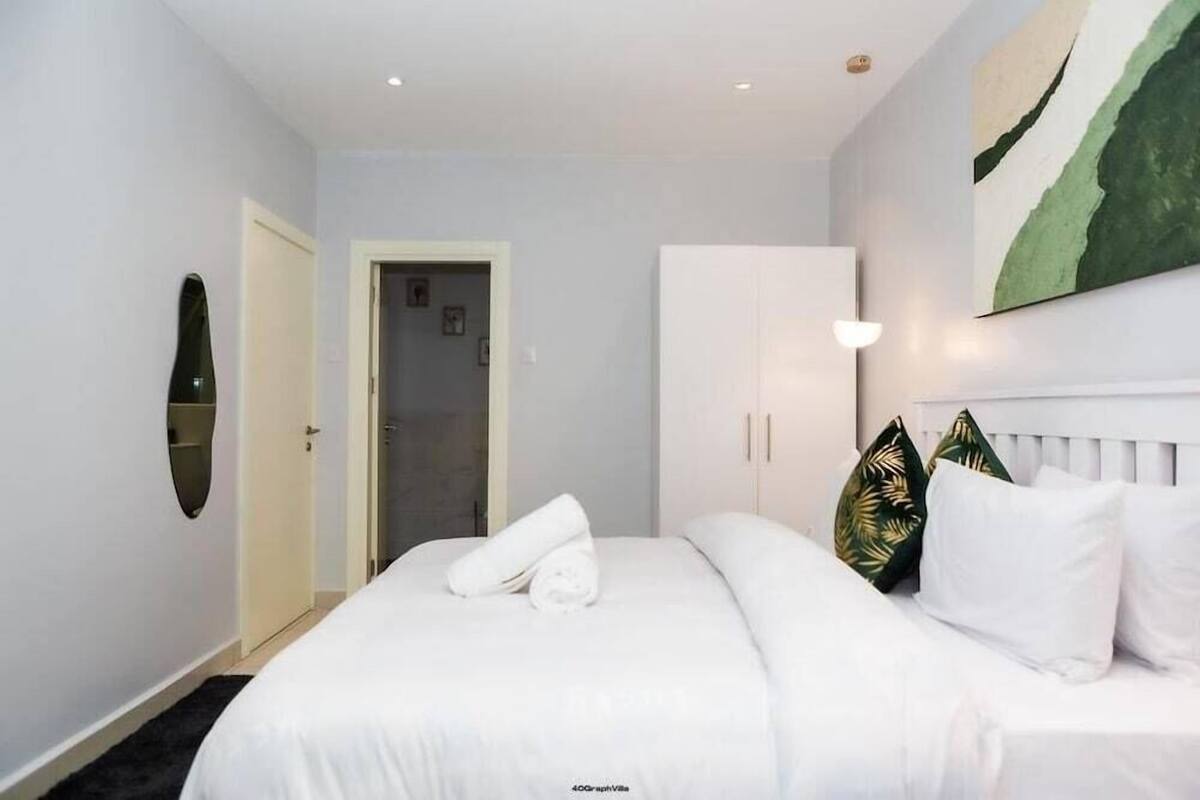 A hotel room with a bed, a wardrobe, a door, and a wall-mounted artwork.