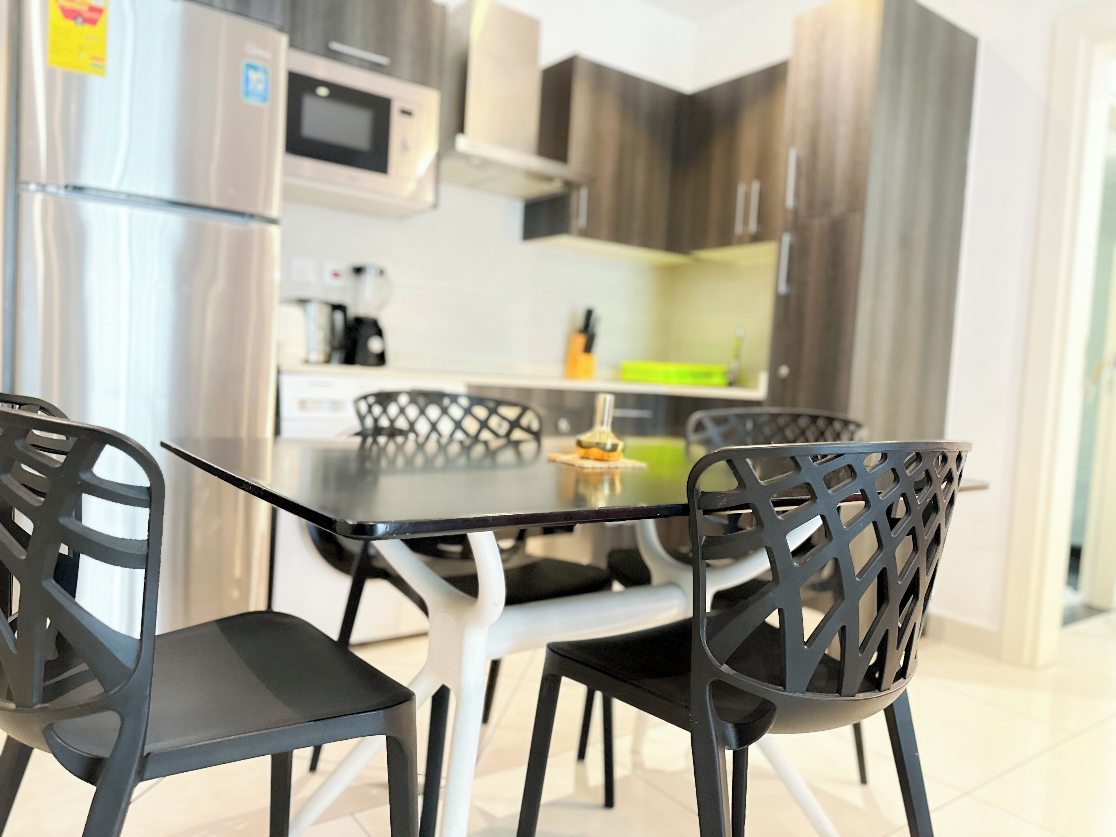 Een moderne keuken met roestvrijstalen apparatuur, een eettafel met glazen blad en zwarte stoelen.