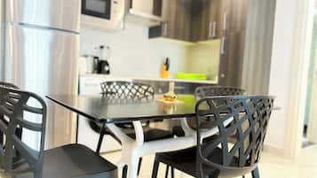 Een moderne keuken met roestvrijstalen apparatuur, een eettafel met glazen blad en zwarte stoelen.