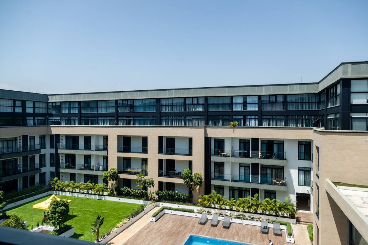 A modern hotel with multiple floors, a courtyard with a pool, and outdoor seating areas.