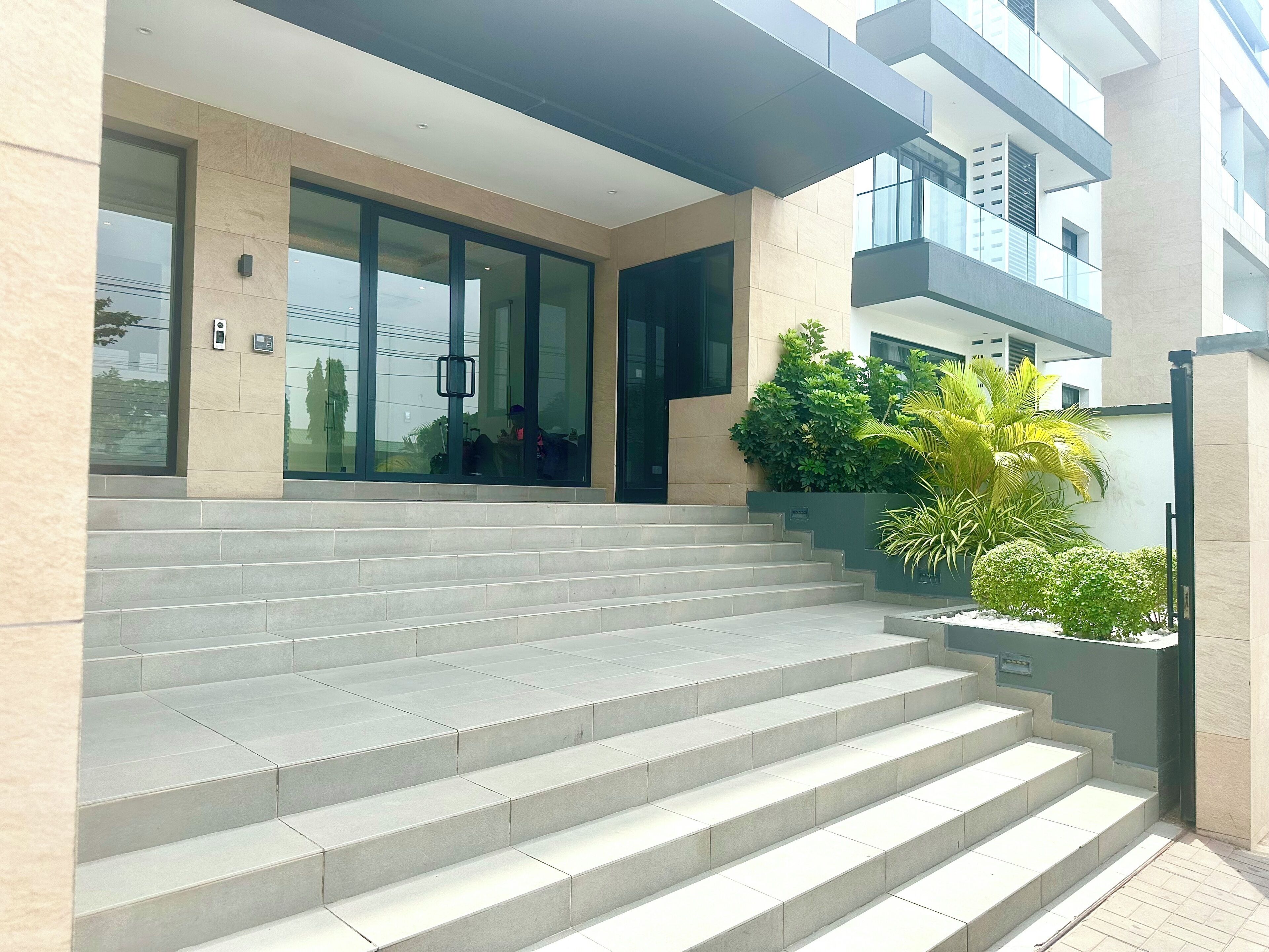 Une entrée moderne, avec un escalier en béton menant à une porte en verre.