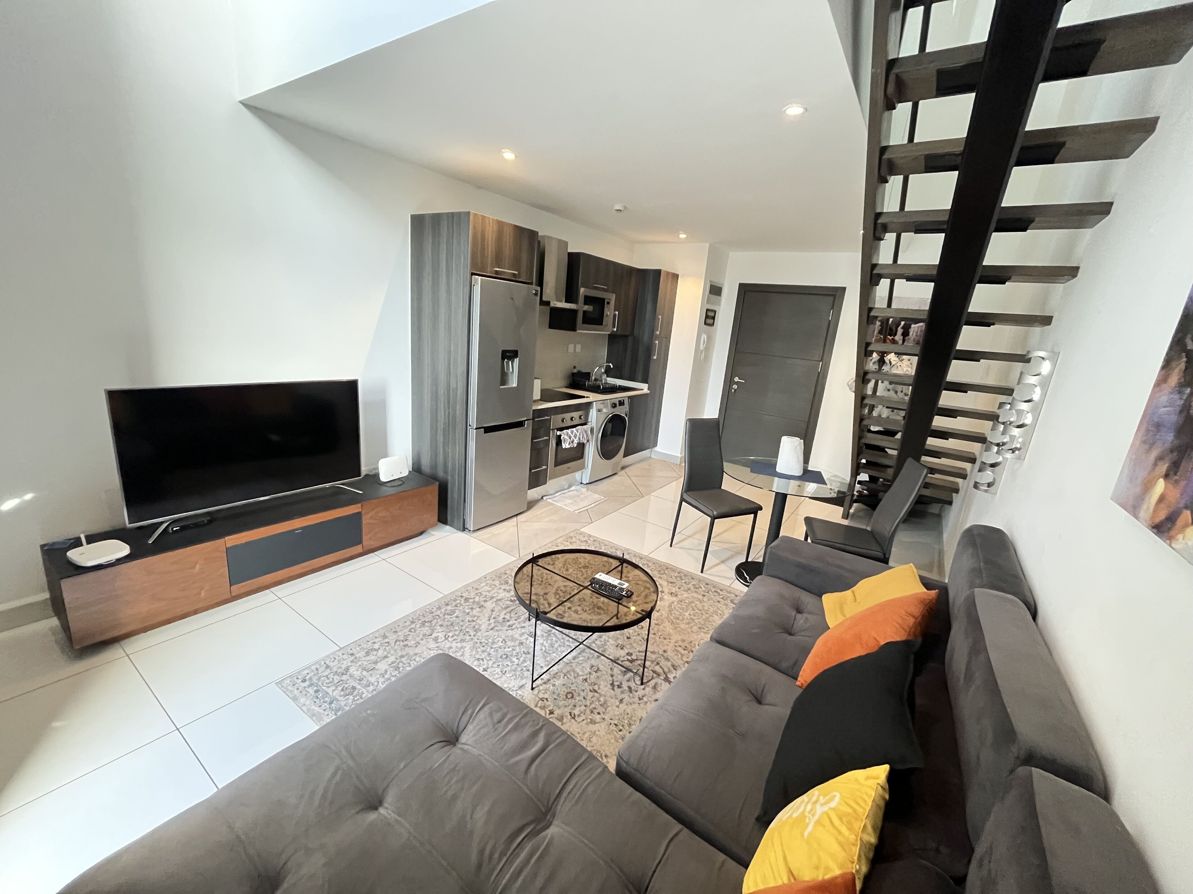 A modern living room with a flat-screen TV, grey sofa, and a coffee table.