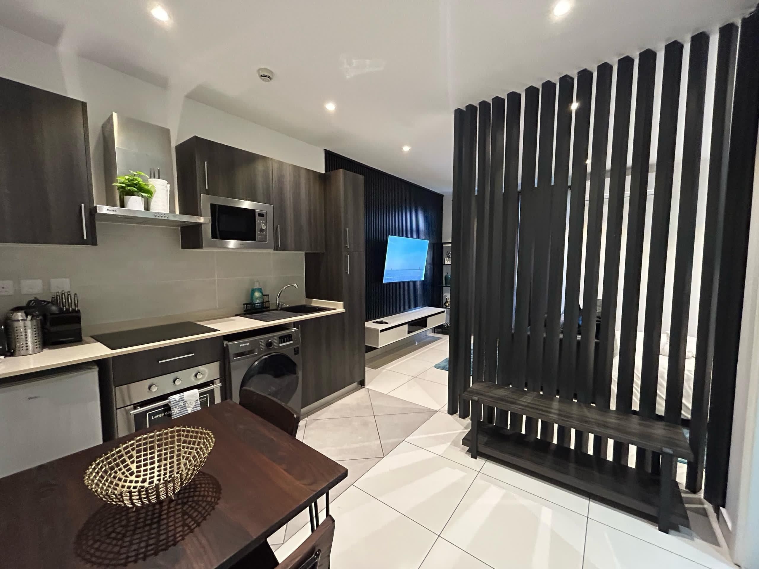 Una cocina moderna con microondas, pileta y lavavajillas. Hay un comedor con mesa y sillas.