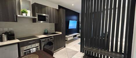 Una cocina moderna con microondas, pileta y lavavajillas. Hay un comedor con mesa y sillas.
