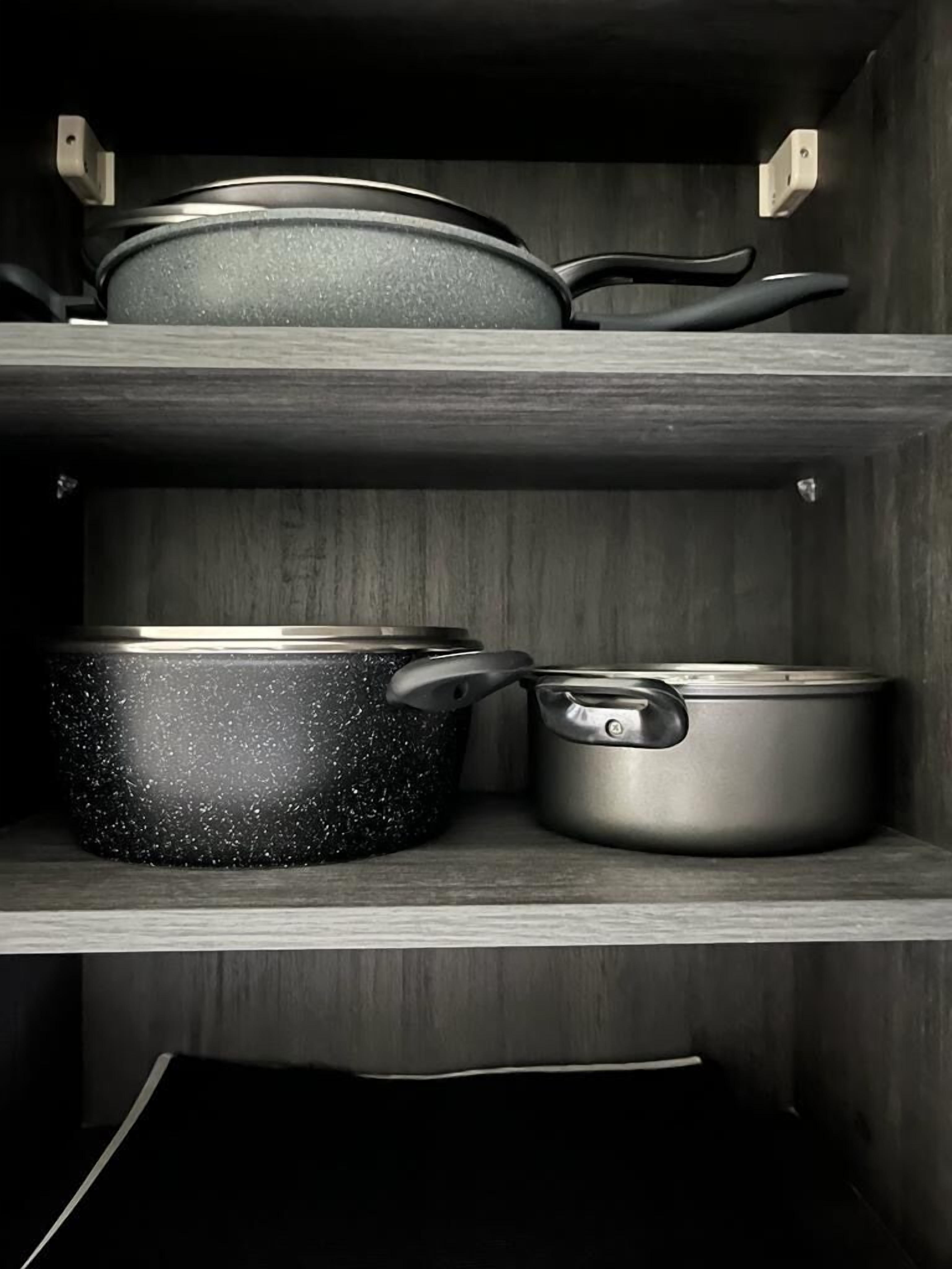 Un meuble de cuisine contenant trois casseroles et trois poêles.