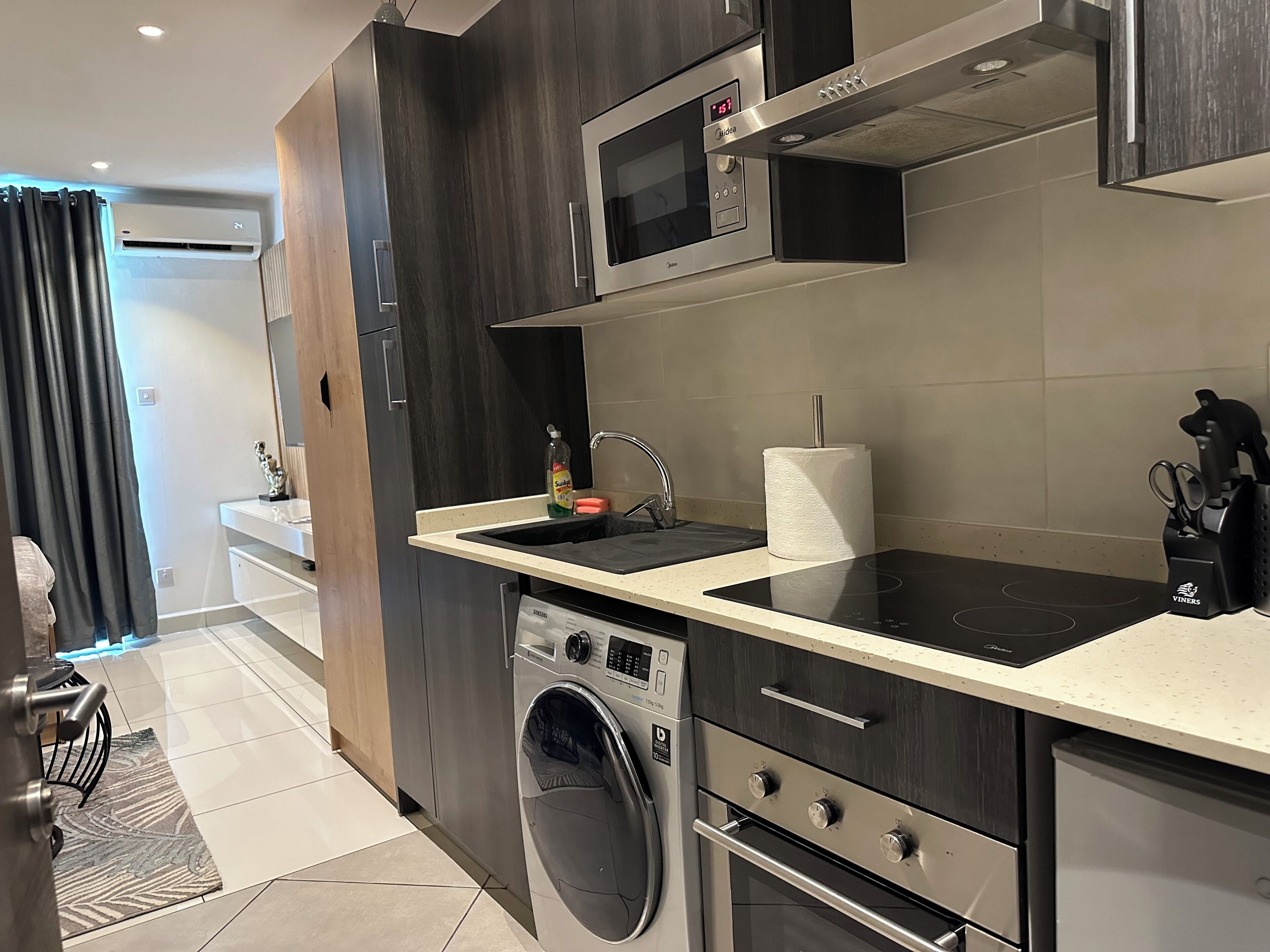 A modern kitchen with a built-in microwave, oven, and washing machine.