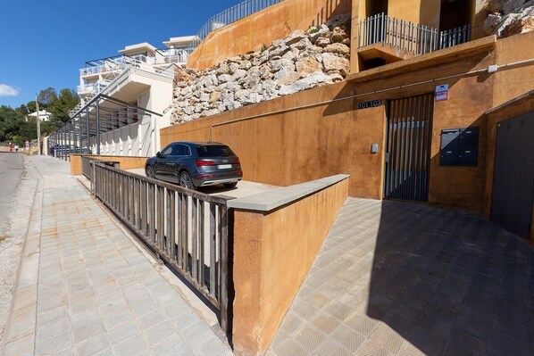 A modern building with a stone facade, a gated entrance, and a parked car. - Villa on Almadrava beach, Roses. Private parking, 200m beach, 3 bedrooms, equipped kitchen, terrace, Wi-Fi, air conditioning. Book now for an unforgettable holiday on the Costa Brava! (Roses)