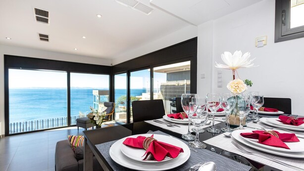 A dining area with a view of the sea, large windows, and a table set for a meal. - Villa on Almadrava beach, Roses. Private parking, 200m beach, 3 bedrooms, equipped kitchen, terrace, Wi-Fi, air conditioning. Book now for an unforgettable holiday on the Costa Brava! (Roses)