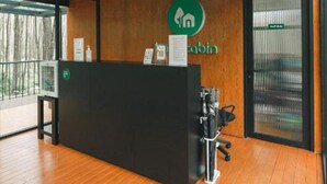 Un mostrador de recepción con suelo de madera, una barra negra y un logotipo en la pared.