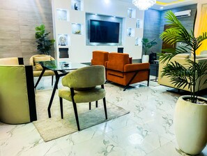 A modern living room with a flat-screen TV, comfortable seating, and decorative items on the walls. - Impeccable 2-Bed Apartment in Lekki With Snooker (Lekki)