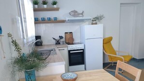 Eine kleine Küche mit Essbereich, einer Kaffeemaschine und einem Kühlschrank.