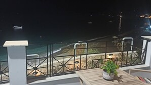 Ein Balkon mit Blick auf den Strand und den Ozean bei Nacht.