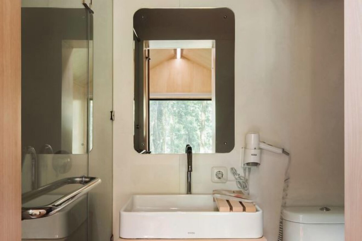 Un baño pequeño con lavamanos, espejo y ventana.