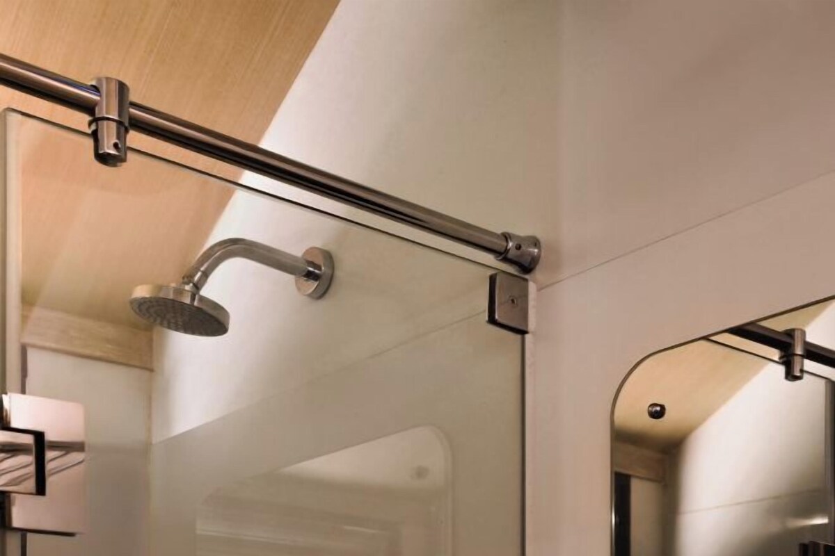 Un baño moderno con cabina de ducha de vidrio, un perchero y un espejo.
