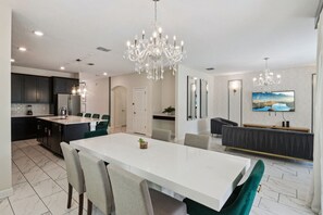 Una cucina moderna con mobili scuri, un'isola bianca e un lampadario.
