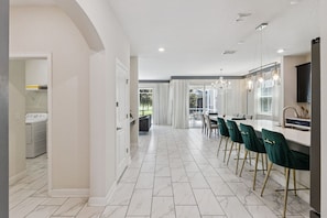 Cozinha moderna com área de jantar, piso de mármore branco e vista para o exterior.