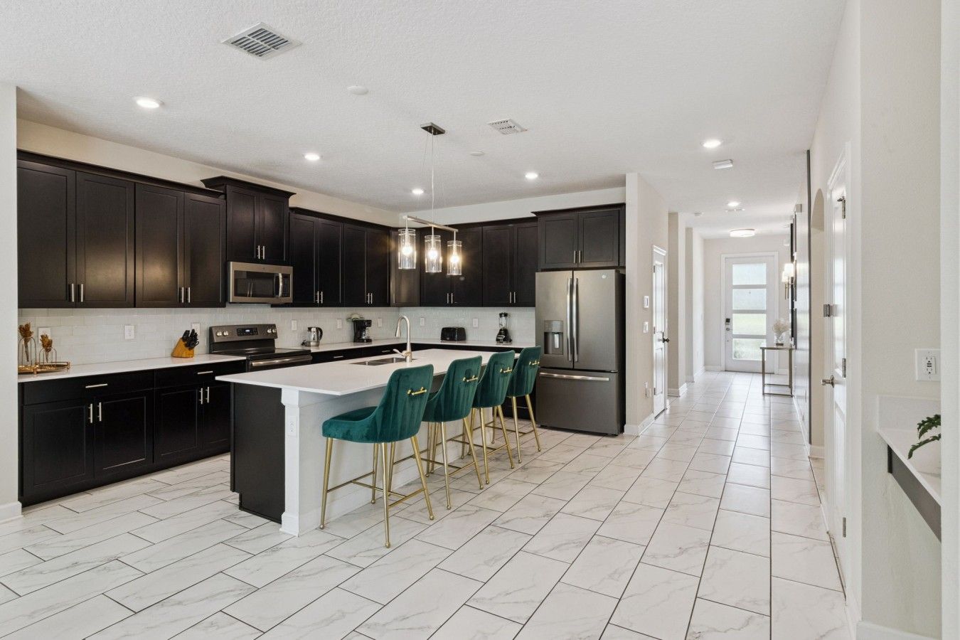 A modern kitchen with dark cabinetry, a central island, and bar-style seating.