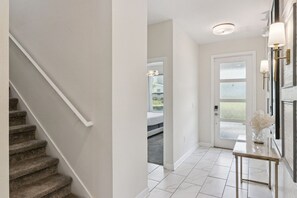 A hallway with a staircase, a door leading to a bedroom, and a small table with a vase. - 6-bedroom luxurious villa Championsgate BBQ (Davenport)