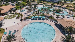 Ein Resort mit einem großen zentralen Pool, umgeben von Liegebereichen und Palmen.