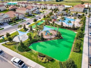 Zona residencial com casas, campo esportivo gramado e piscina.