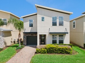 A modern two-story house with a stone facade, a paved driveway, and a well-maintained lawn. - 6-bedroom luxurious villa Championsgate BBQ (Davenport)