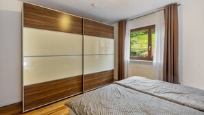 A bedroom with a bed, a sliding wardrobe, and a window with curtains.