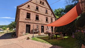 A traditional brick building with a large overhang and a paved courtyard.