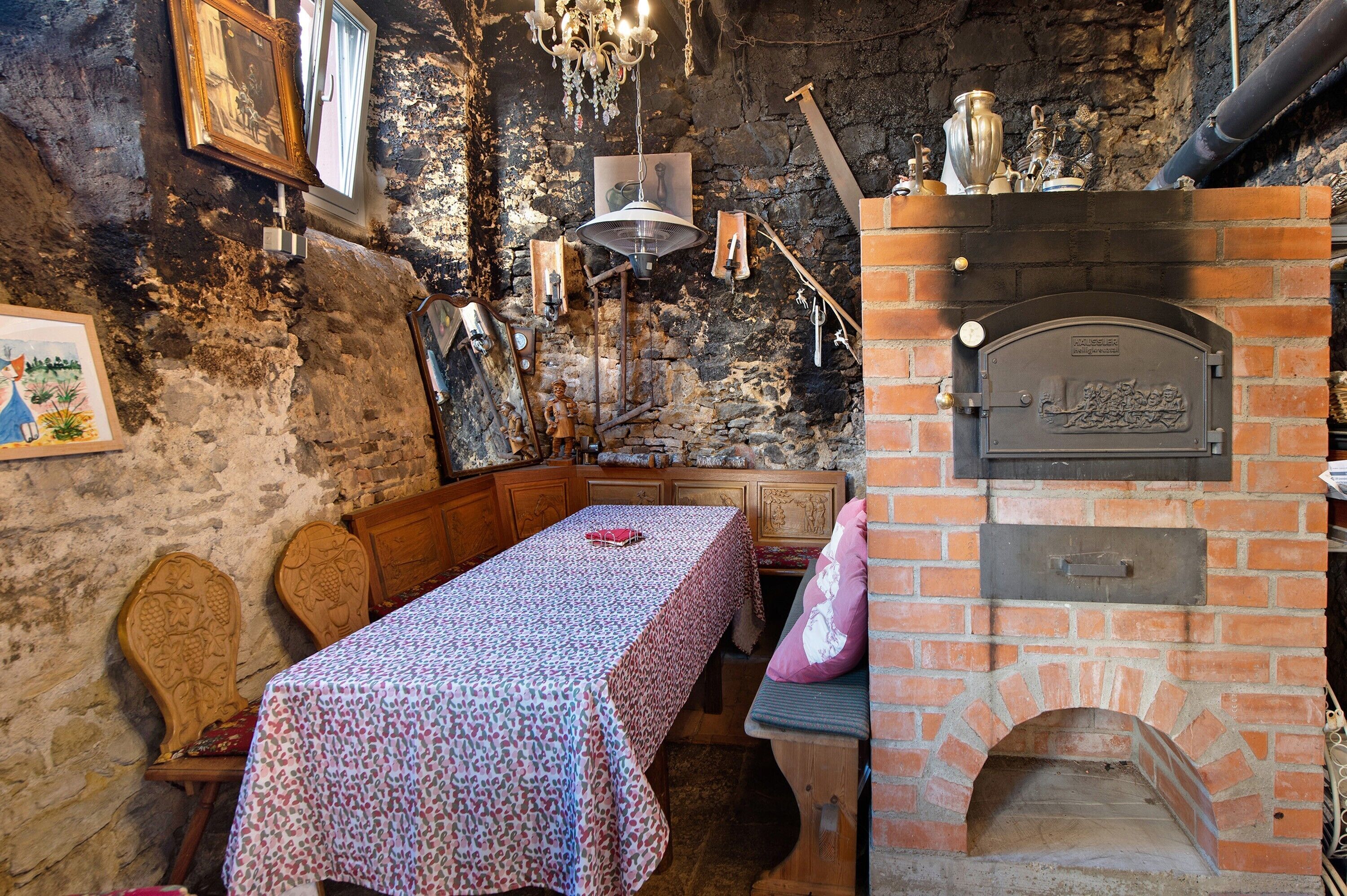 A rustic room with a brick fireplace, wooden furniture, and a table with a patterned tablecloth.