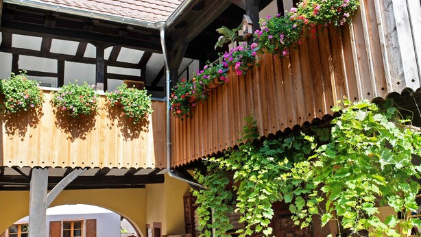 A traditional wooden building with a balcony adorned with hanging flower baskets.