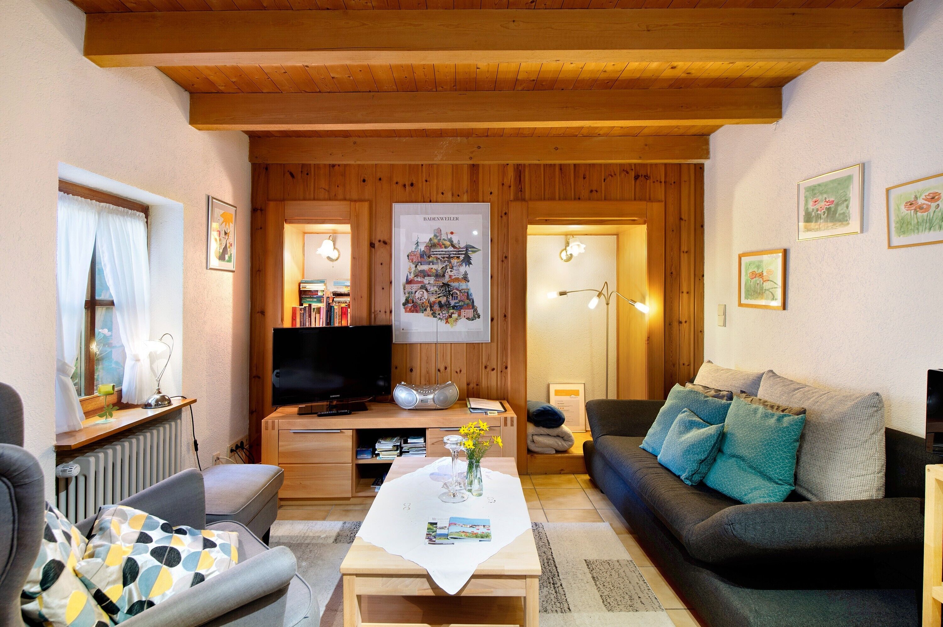 A living room with a wooden ceiling, a sofa, a coffee table, and a television.
