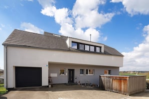 A modern two-story house with a garage, a small porch, and a view of the countryside. - Holiday Apartment "Glüxnest" with Private Terrace, Shared Garden, Sauna and Wi-Fi (Bernstadt)