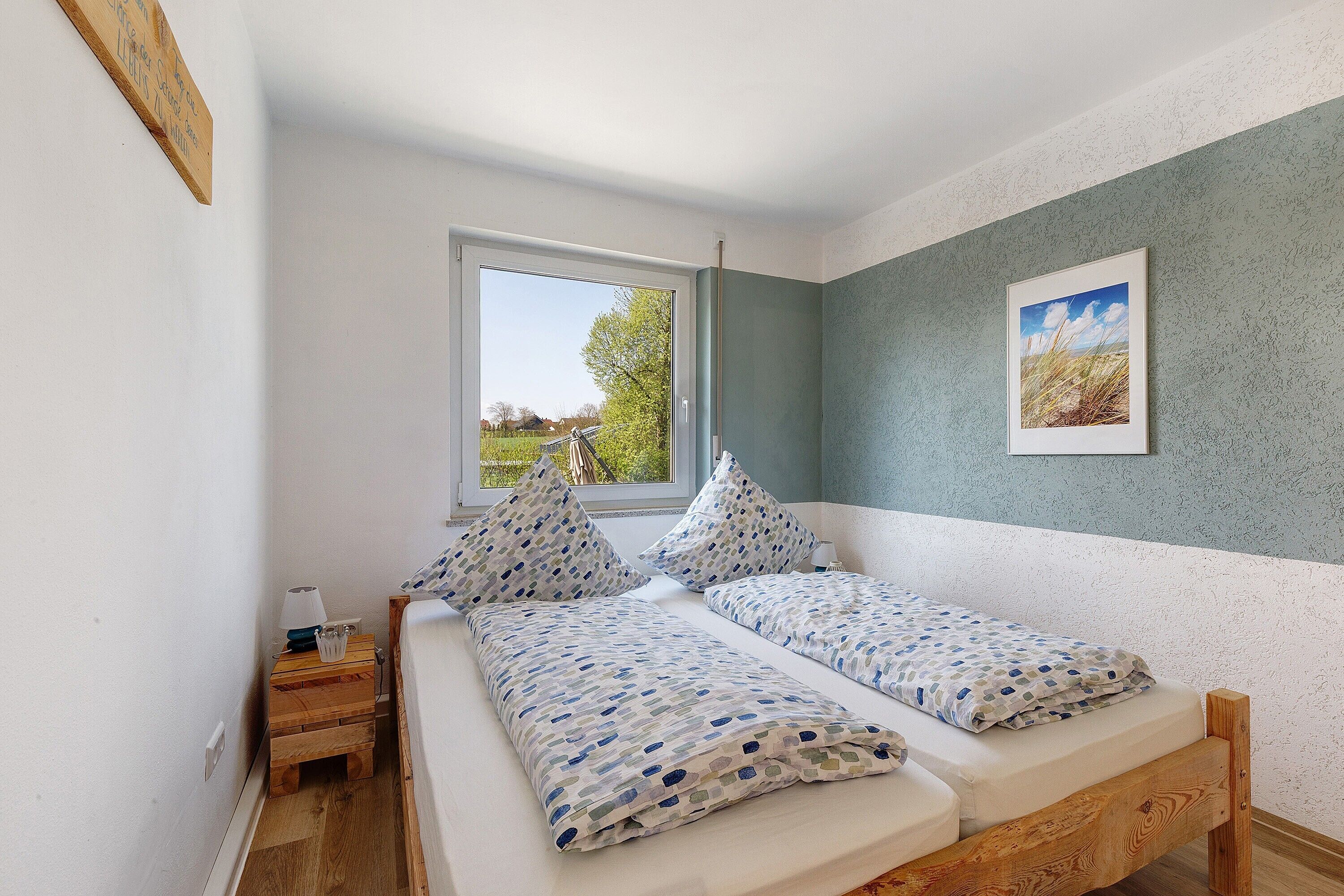 Une chambre à coucher avec un lit, deux oreillers, une table de chevet avec une lampe et une fenêtre.
