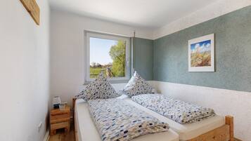 Une chambre à coucher avec un lit, deux oreillers, une table de chevet avec une lampe et une fenêtre.