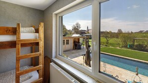 Una habitación con literas, un ventanal y vista a una piscina y zona exterior.