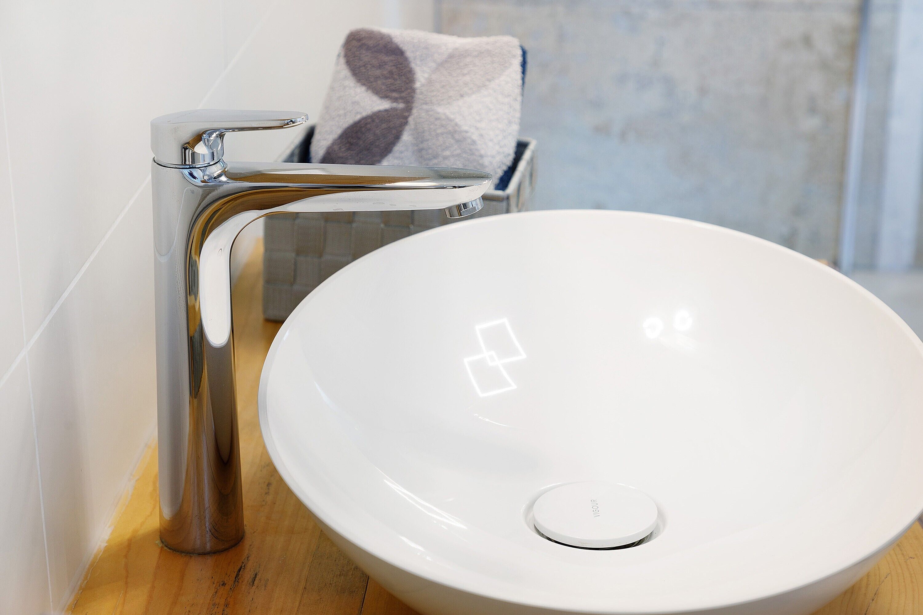 Un bany modern amb un lavabo blanc, aixeta cromada i una barra tovalloles amb una tovallola estampada.