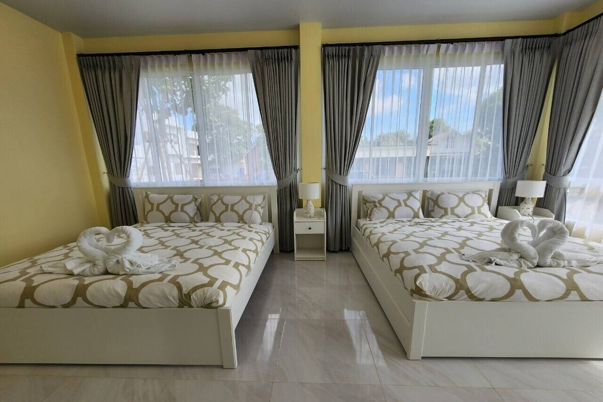A hotel room with two beds, a nightstand, and a window with curtains.