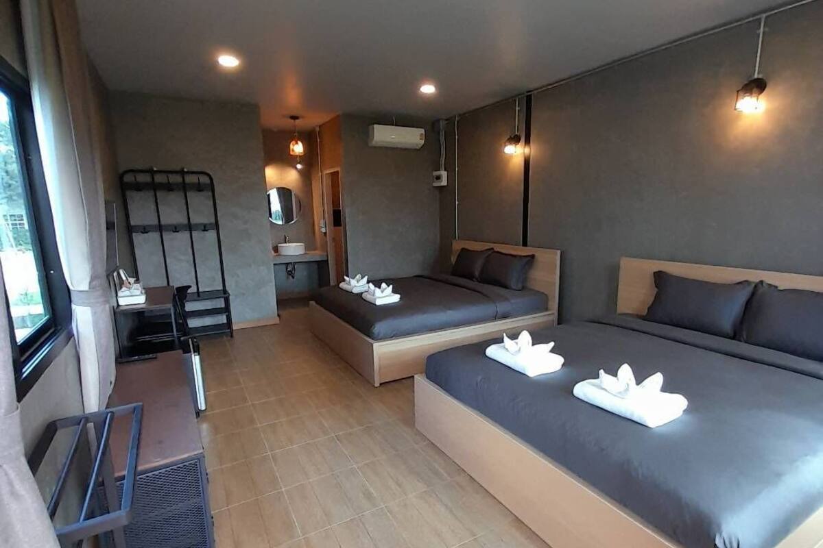 A modern hotel room with a large bed, a smaller bed, a desk, and a seating area.