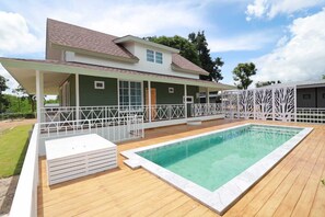 Una casa con piscina, un porche cubierto y una terraza cercada.