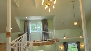 A spacious loft with a high ceiling, exposed wooden beams, a staircase, and multiple windows. - Thungtheiyngvalley Khaoyai (Pak Chong)