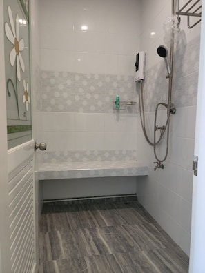 Zona de ducha con asiento, cabezal de ducha manual y grifo empotrado.