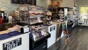 Un comptoir de boulangerie avec un menu, une machine à café et un espace pour récupérer les commandes.