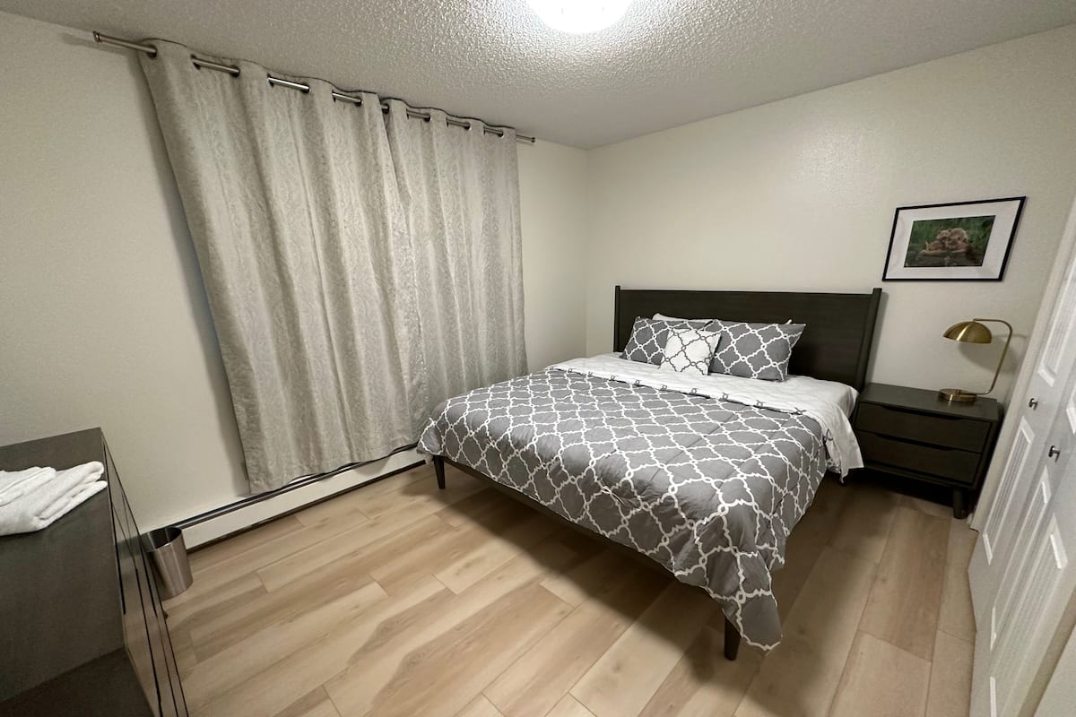 A neatly arranged bedroom with a bed, bedside table, and a small cabinet.