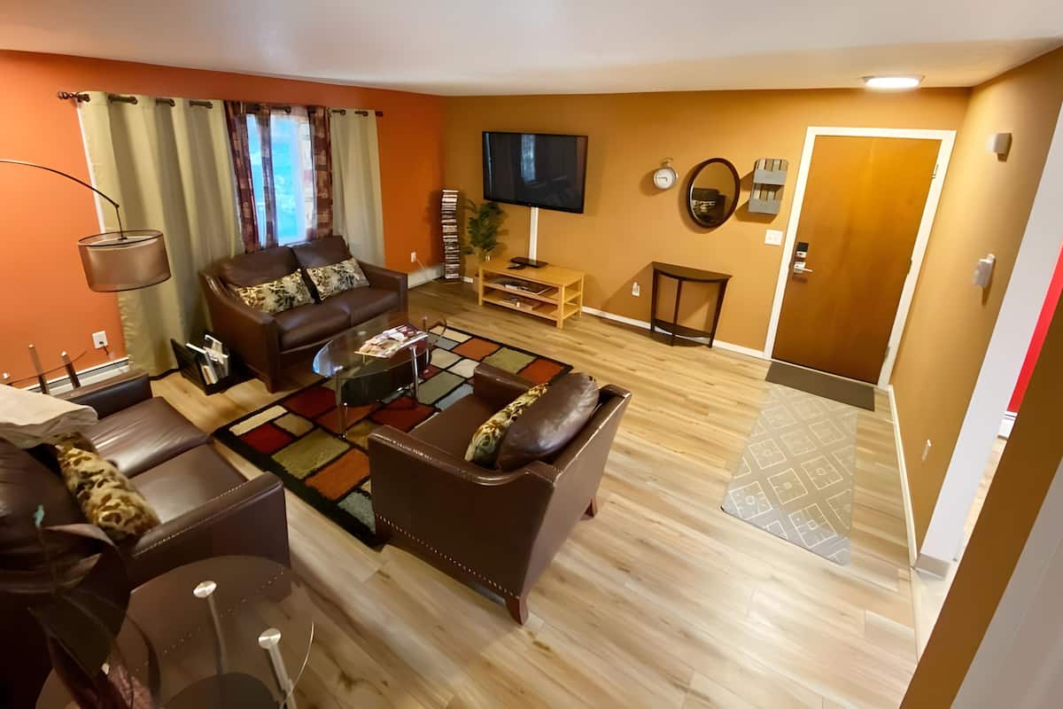 A living room with a brown leather sofa, a glass coffee table, and a patterned rug.
