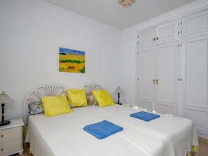 A bedroom with a bed, white wardrobe, and a painting on the wall. - El Chaparral by Interhome (Coin)